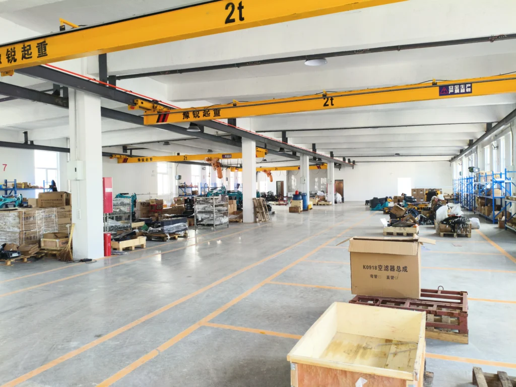 Pemandangan luas bengkel pabrik dengan derek dan mesin di atas kepala