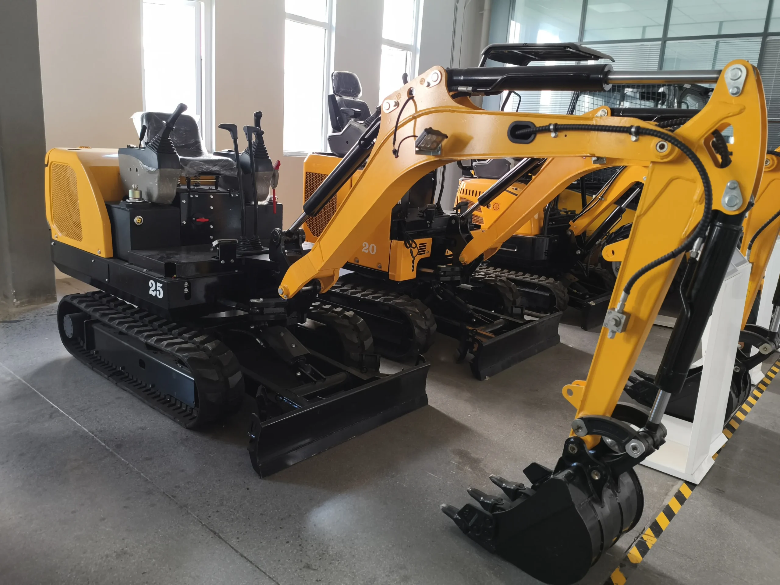Yellow mini excavator parked in an indoor factory bay